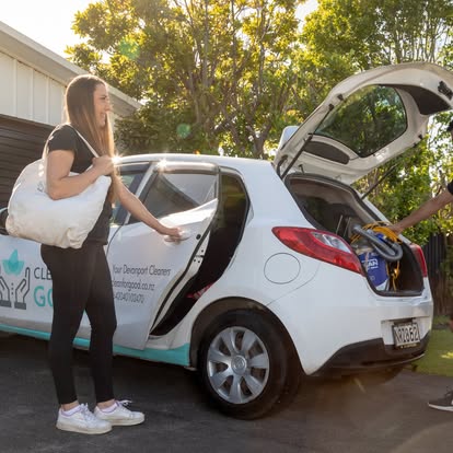 A Clean for Good team member loading cleaning supplies into the branded Devonport car on the street